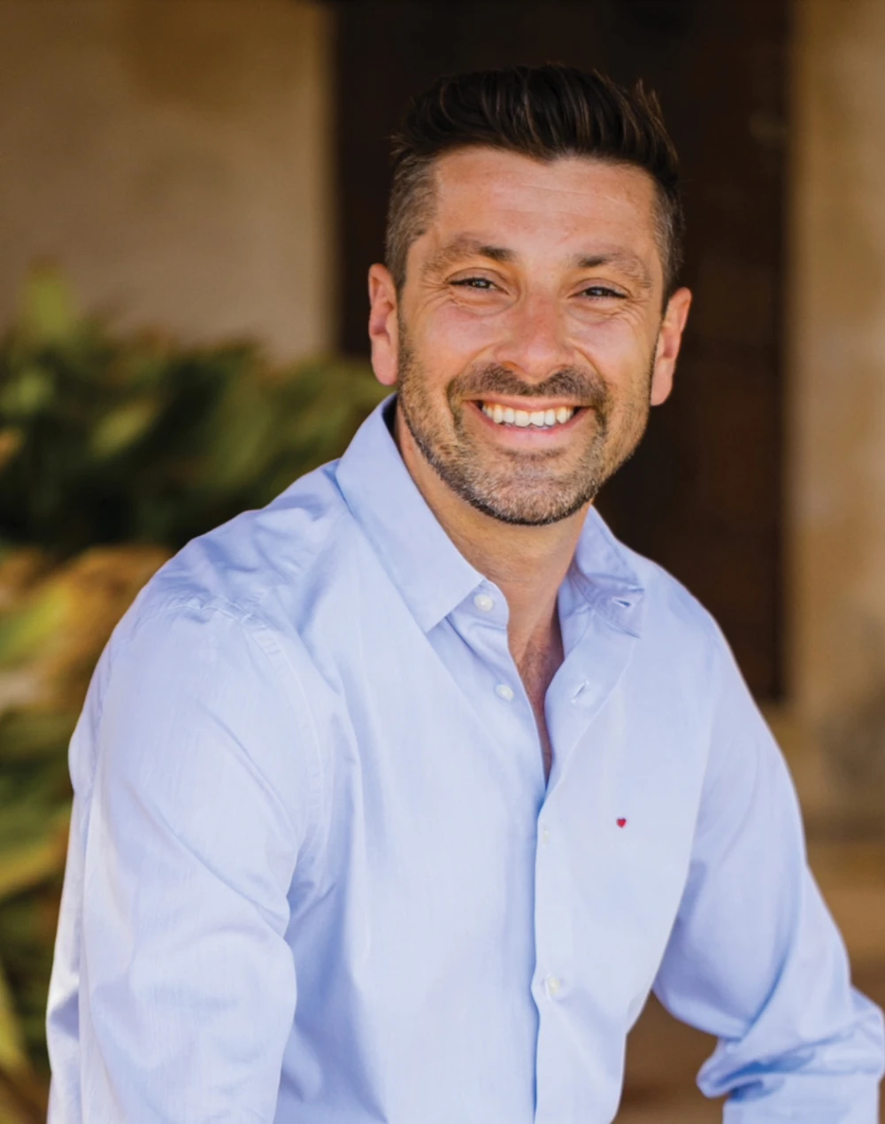 Julian Cunningham-Bond con una camisa azul y sonriendo. 