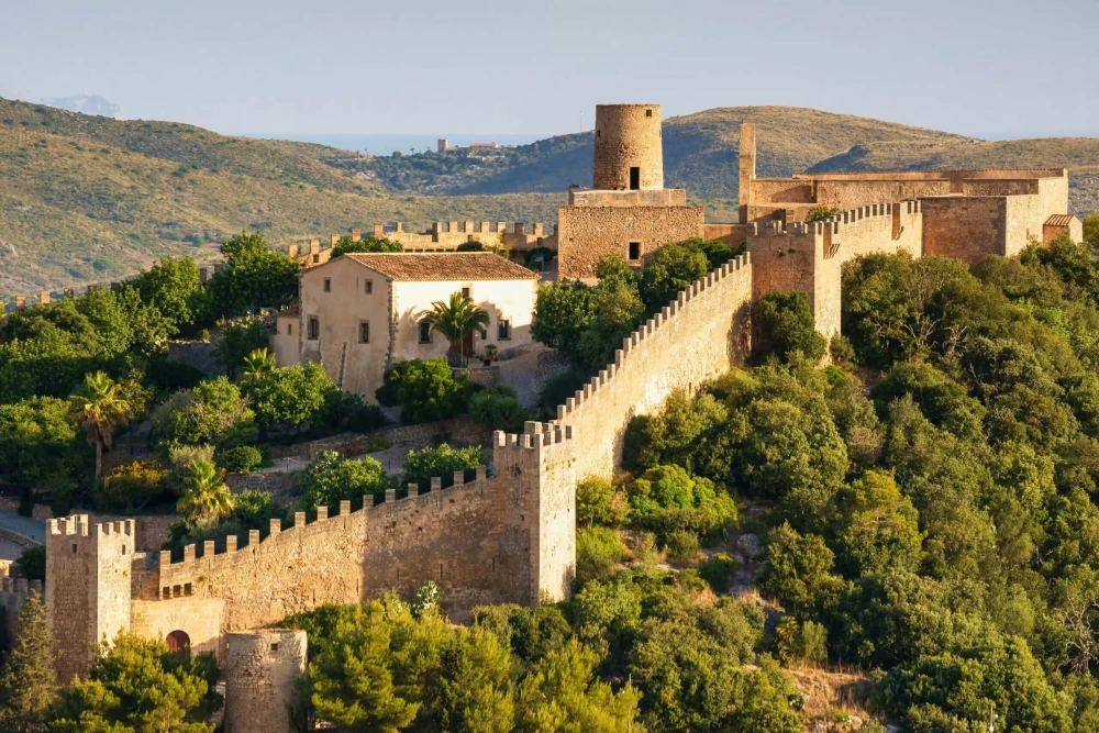 Castillo histórico en lo alto de una colina y arquitectura tradicional de piedra en Capdepera